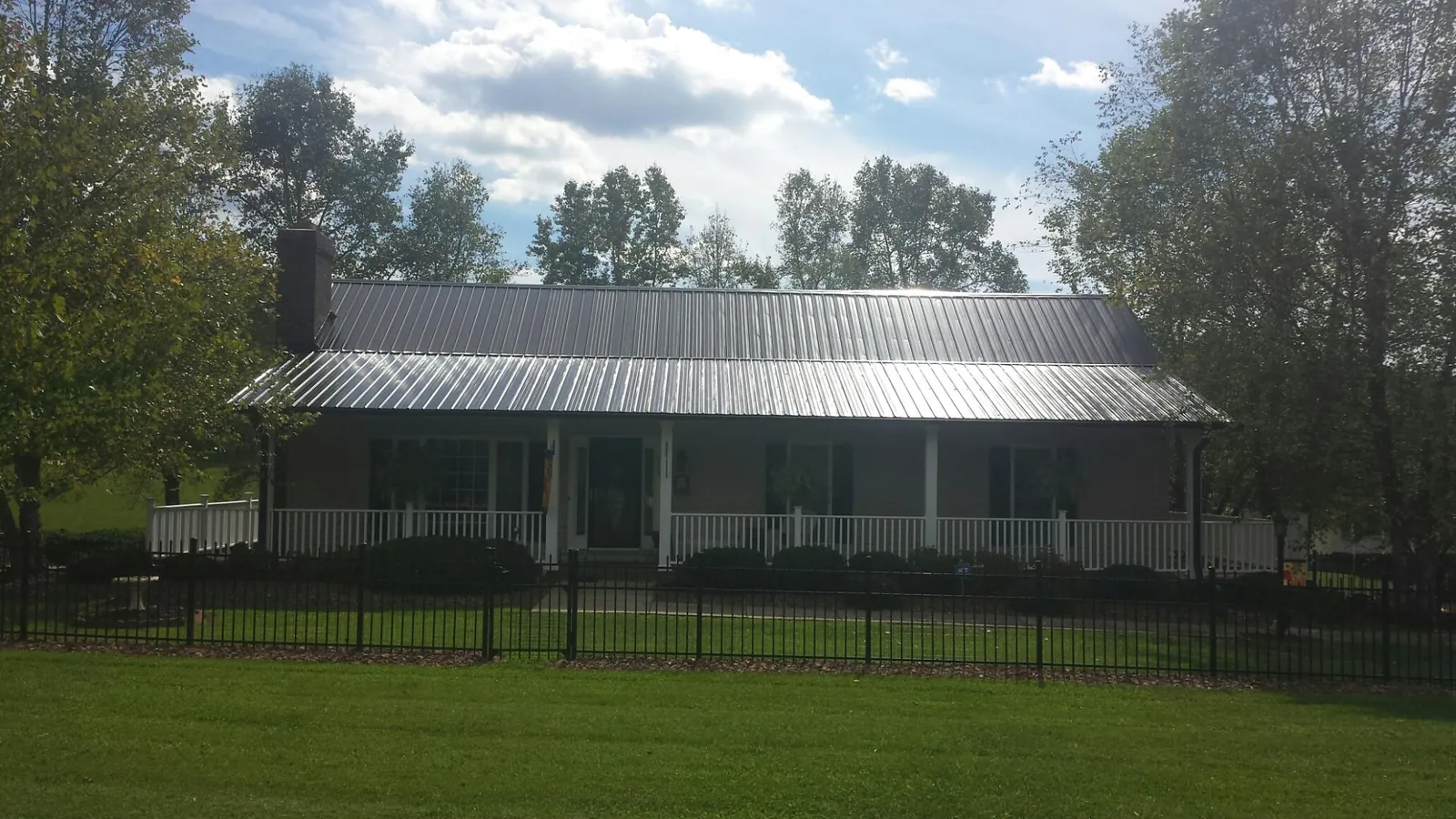 Gray metal roof on a brick ranch with a full width front porch — Gutter Guard Installation work by our crew in Timmonsville