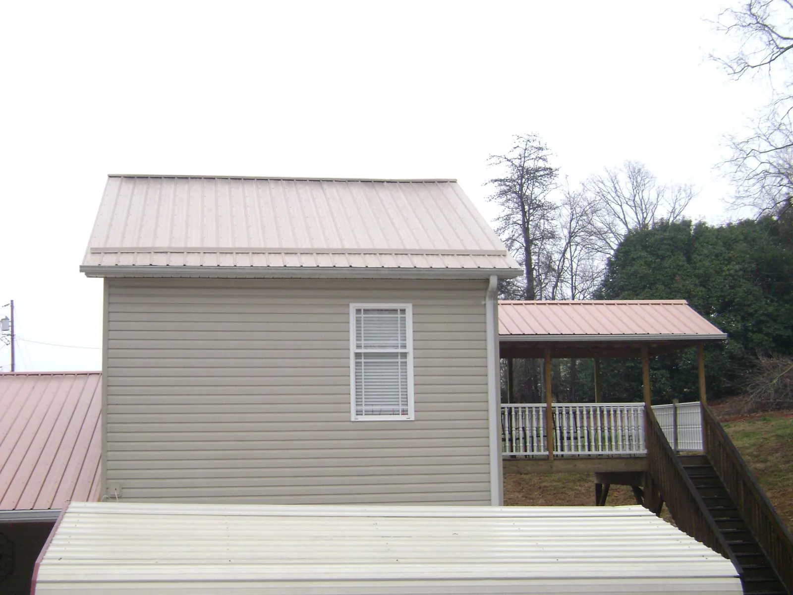 Tan metal roofs on a two story addition and attached porch, from a Roof Replacement job in Timmonsville