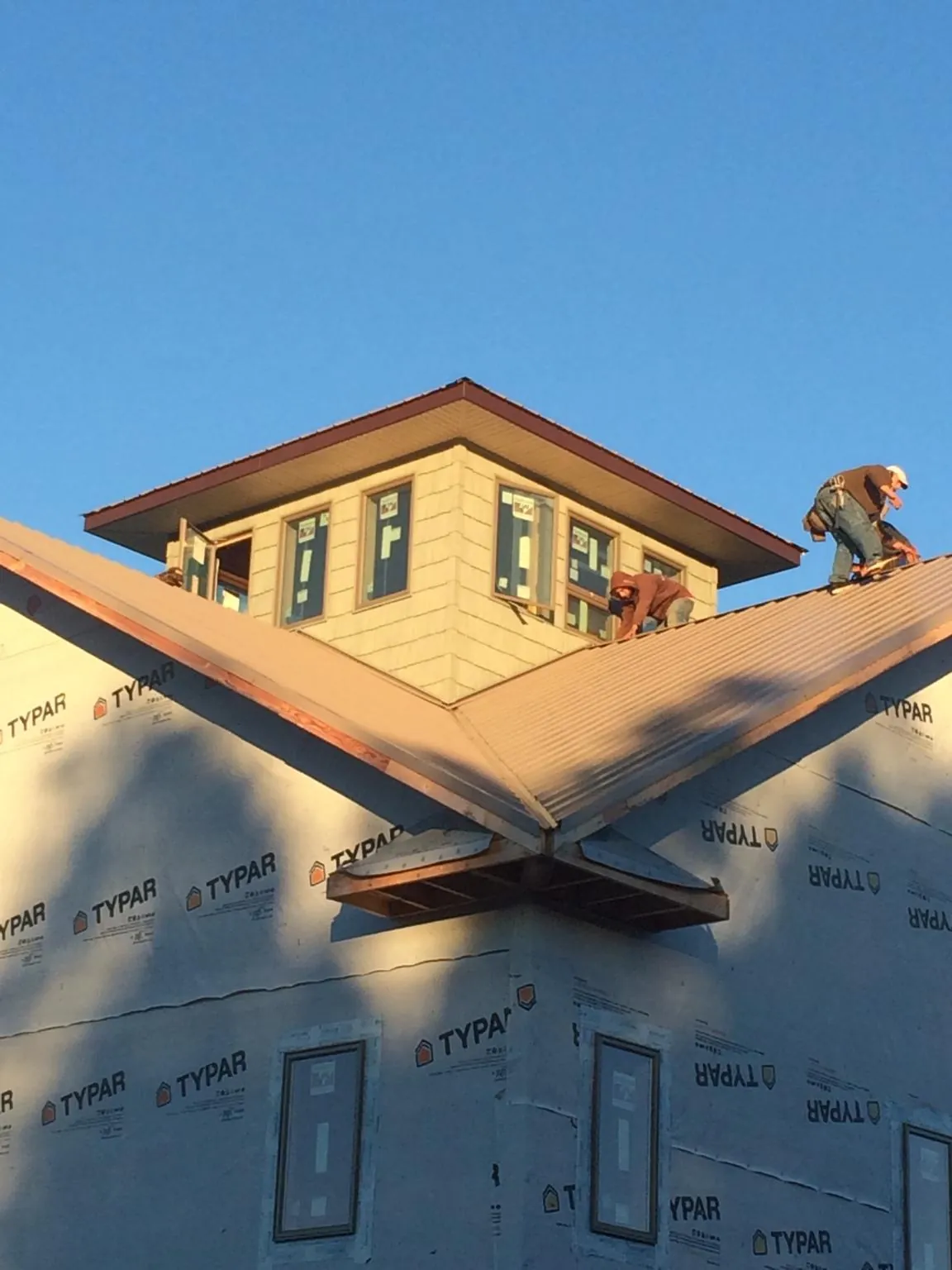 Roofers working around a rooftop cupola on a new metal roof at sunset — Roof Waterproofing in Timmonsville by Roofing Brothers